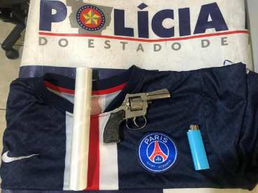 Foram apreendidos no quarto do suspeito um revólver calibre 22 da marca Bagual e a camisa azul escura, do time Paris Saint-Germain Foot Ball Club, utilizada pelo suspeito na vídeochamada
