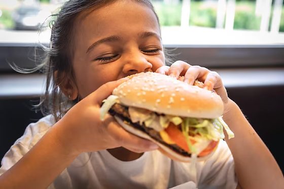 Criança comendo hamburguer