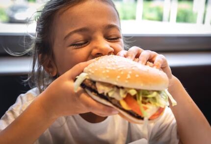 Criança comendo hamburguer